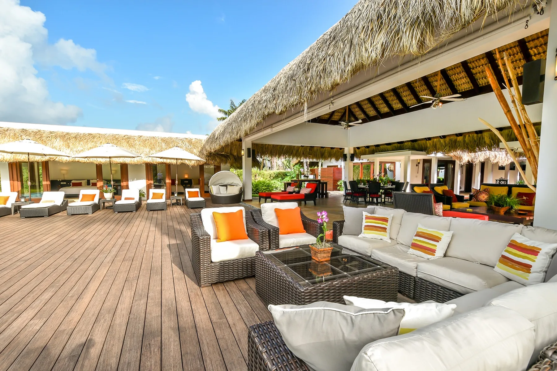 Un salón al aire libre con asientos acolchados y una terraza de madera.