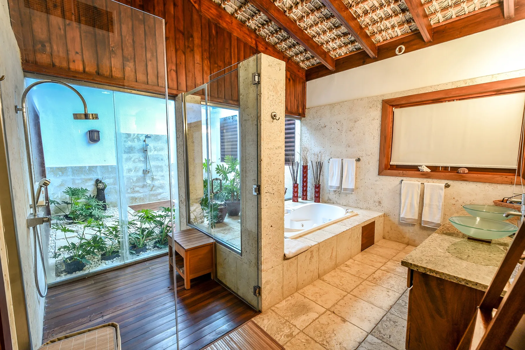 Un baño con bañera, ducha de vidrio y un espejo grande.
