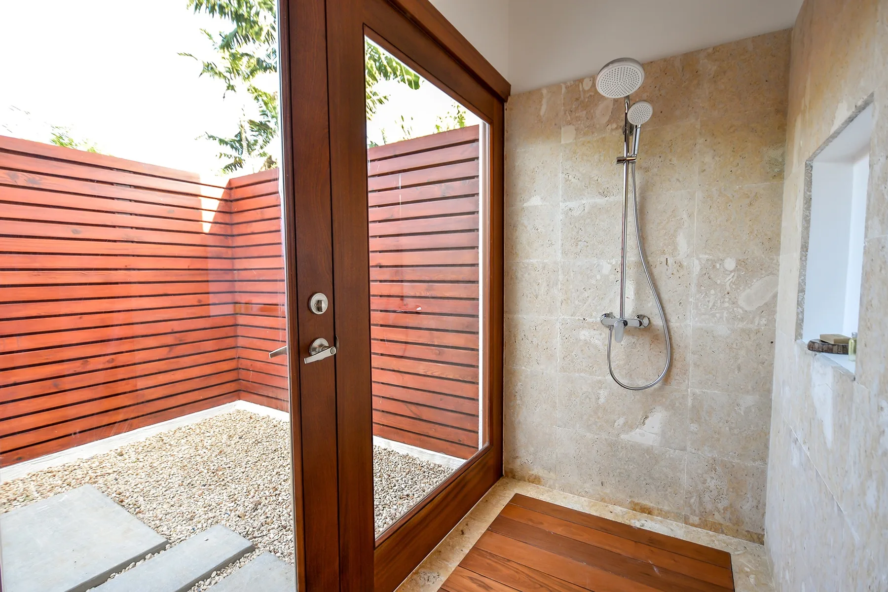 Una ducha al aire libre con ducha de pared y pantallas de madera.
