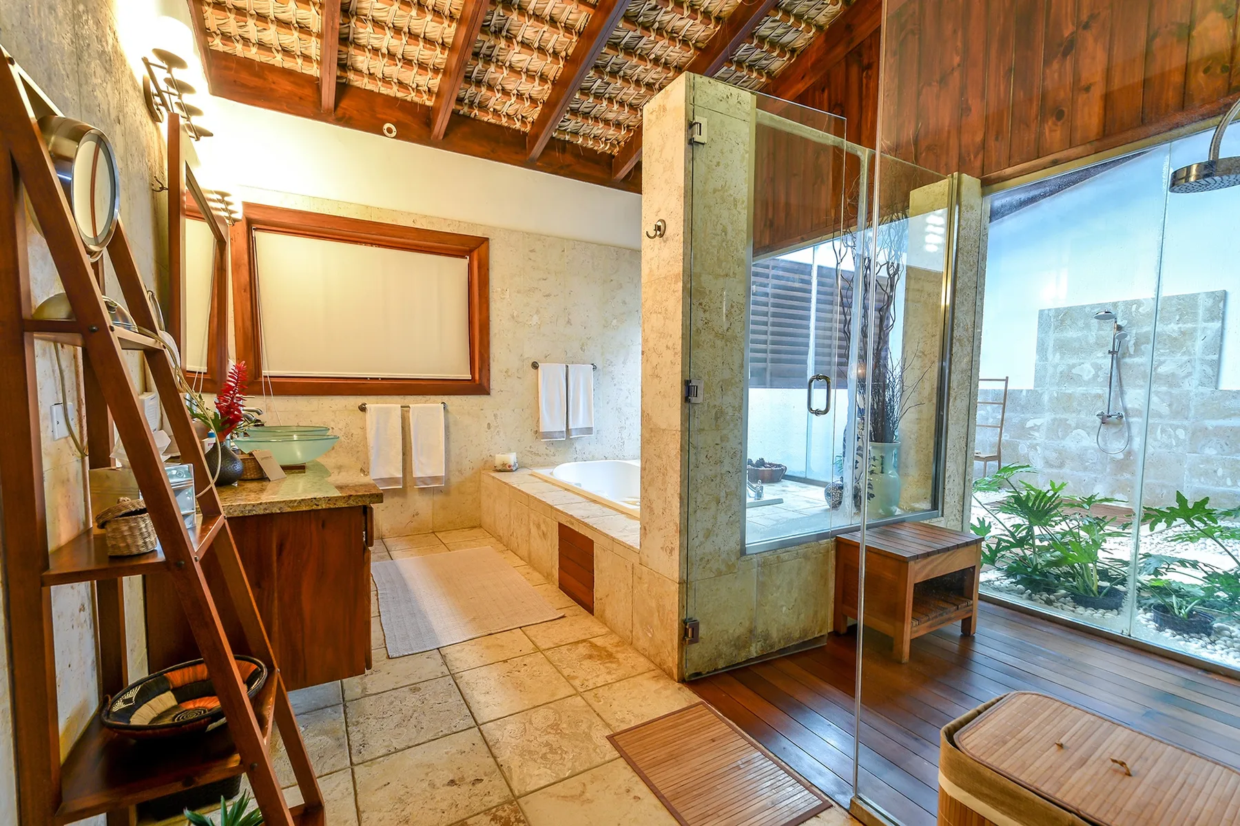 Un baño amplio con lavabo, bañera y ducha de vidrio junto a grandes ventanales.