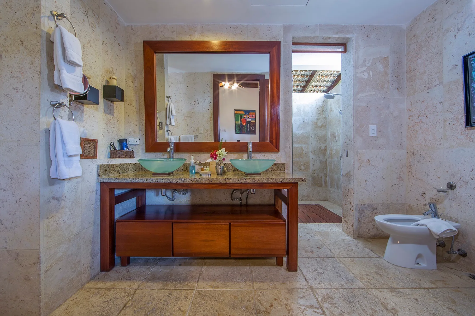 Un baño con azulejos de piedra, lavabo doble y ducha.