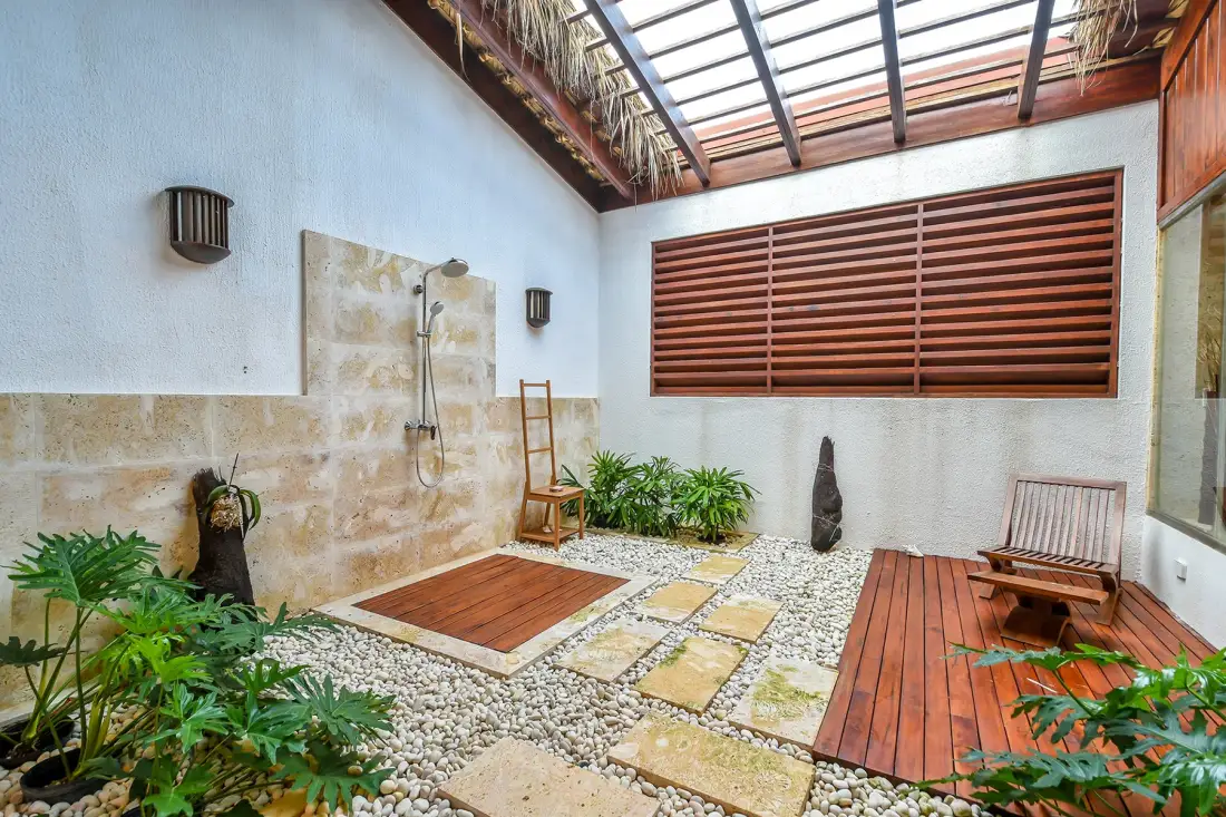Un baño al aire libre con ducha, suelo de guijarros y tarima de madera.