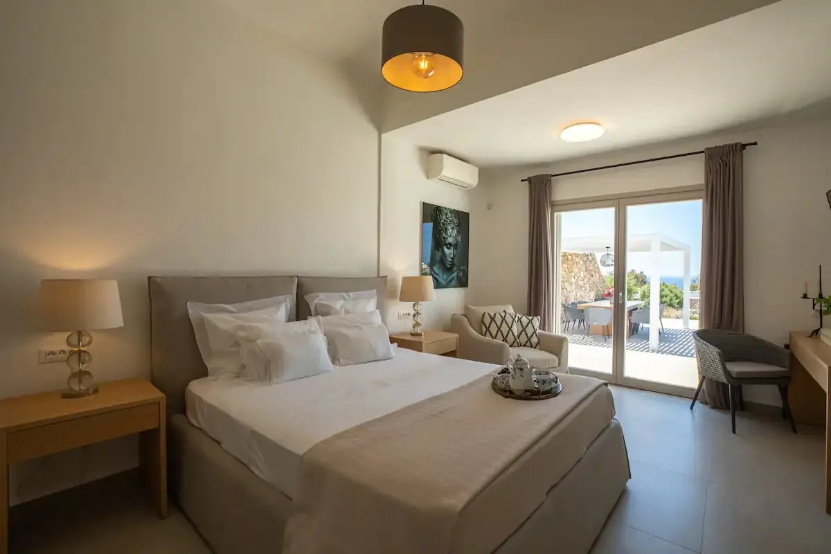 Dormitorio con una cama grande y puertas corredizas de vidrio que dan a un patio.