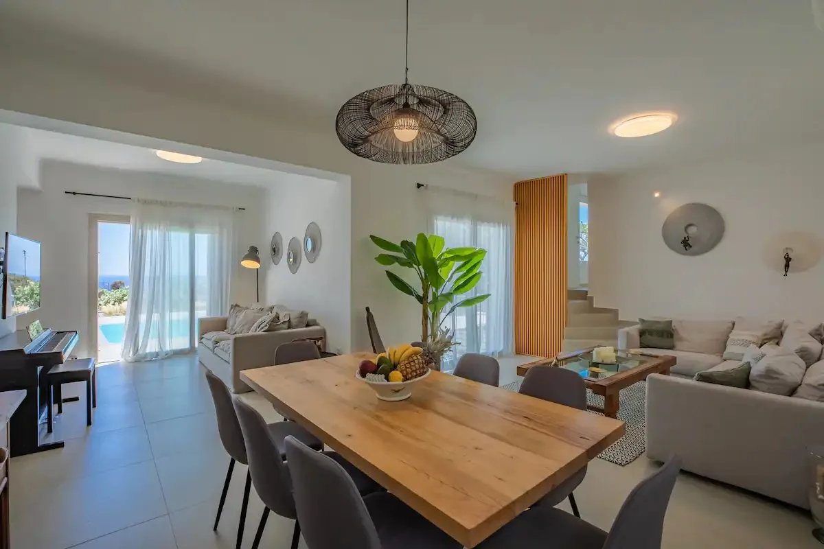 Sala de estar y comedor de concepto abierto con mesa de madera y asientos.