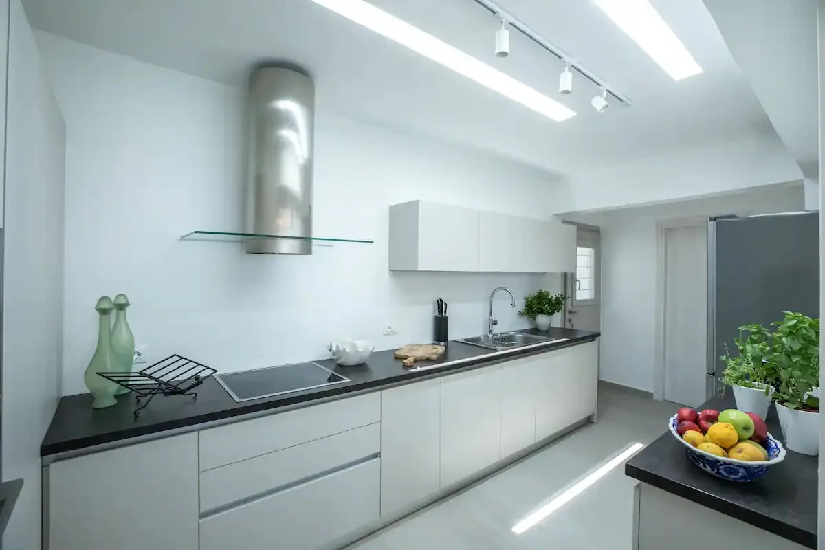 Una cocina moderna y luminosa con gabinetes blancos y una encimera oscura alargada.