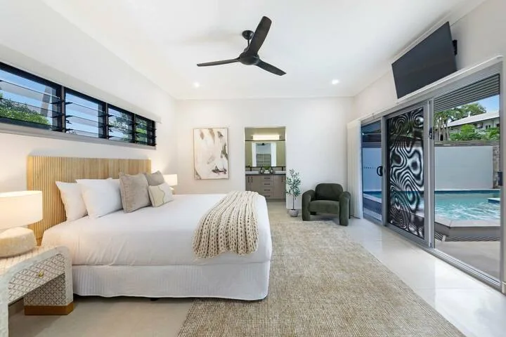 Un dormitorio luminoso con una cama grande y puertas corredizas de vidrio hacia una piscina.