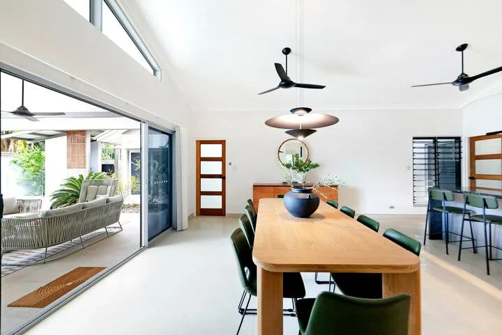 Un comedor luminoso con una larga mesa de madera junto a puertas corredizas de vidrio.