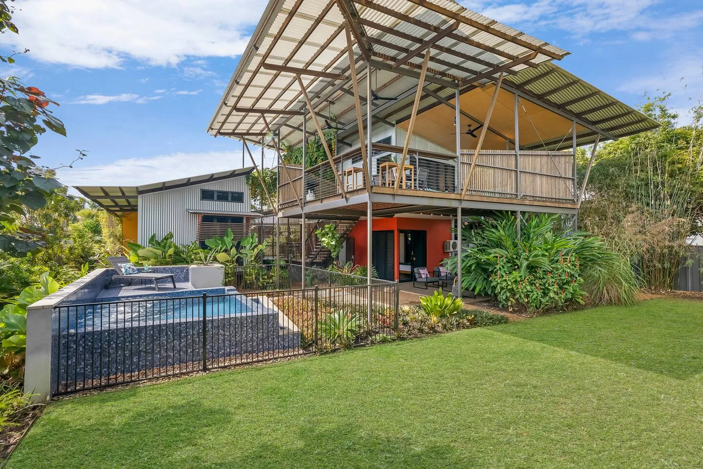 Una impresionante combinación de diseño moderno y vegetación tropical crea un espacio exterior acogedor y aireado, perfecto para relajarse y recibir invitados.