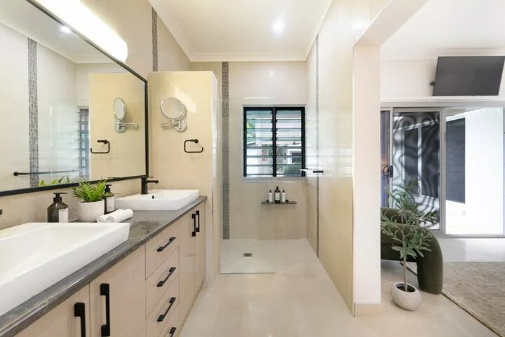 Un baño luminoso con un tocador largo, un espejo grande y una ducha.