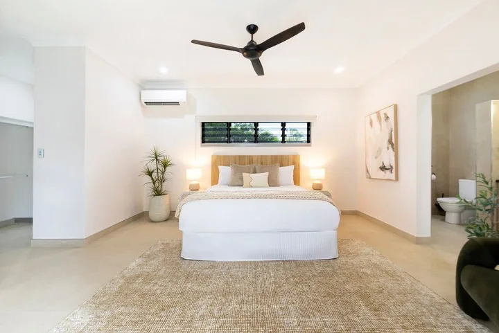 Un dormitorio luminoso con una cama bien tendida y una alfombra grande.