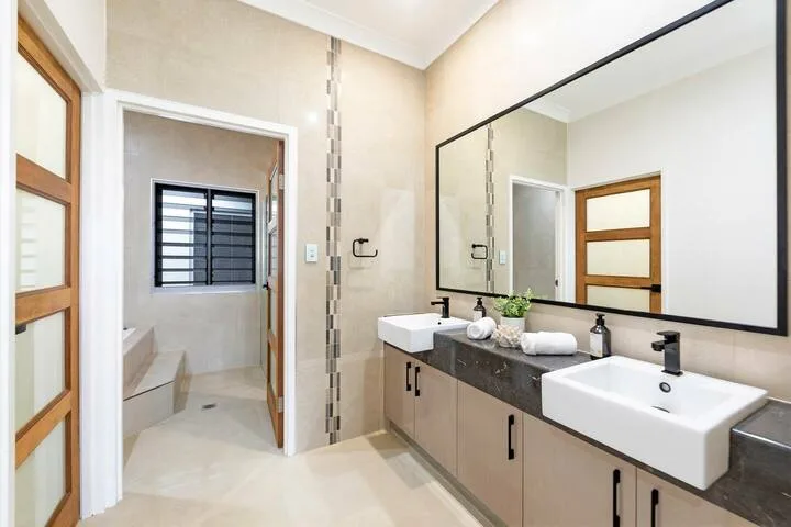 Un tocador de baño con un espejo amplio y una entrada a la zona de ducha.