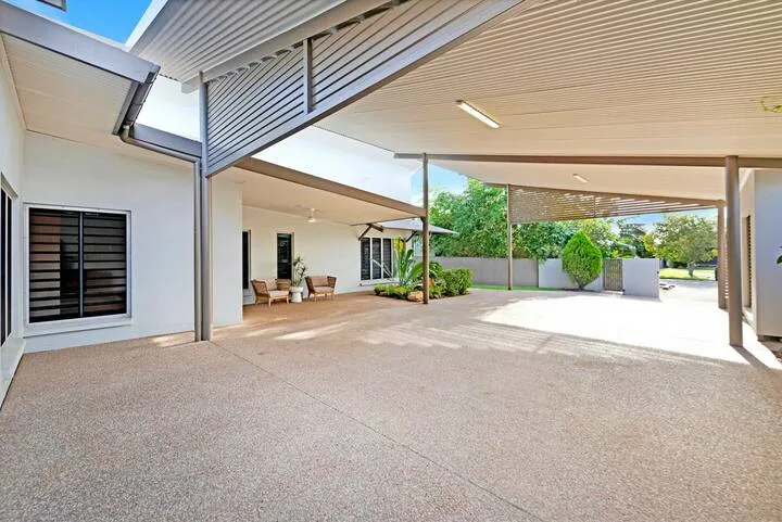 Un patio exterior cubierto con una amplia zona pavimentada y vistas al jardín.