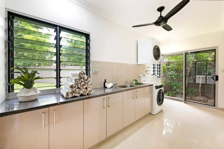 Una cocina luminosa con una encimera larga bajo grandes ventanas.