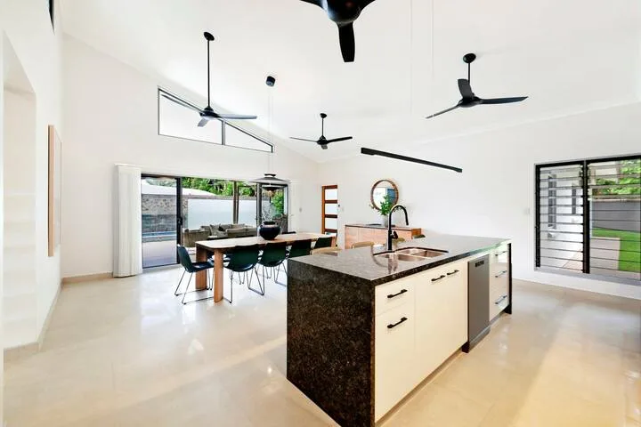 Una cocina y comedor abiertos y luminosos, con una isla central y grandes ventanas.
