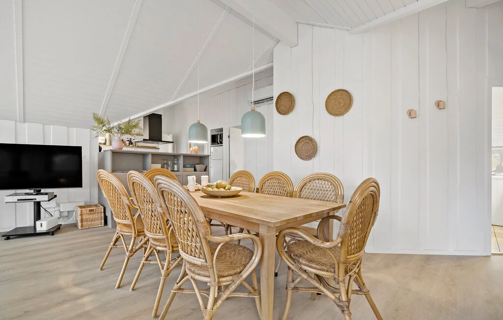 A dining area with a long wooden table and woven seating.