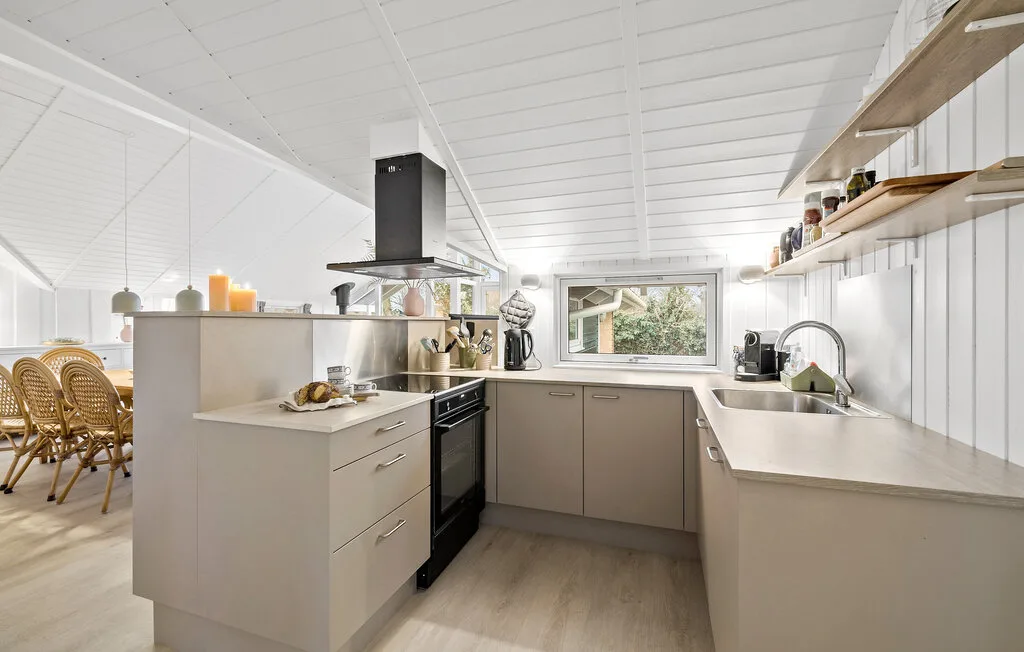 A bright kitchen with pale cabinetry, a central island, and a window above the sink.