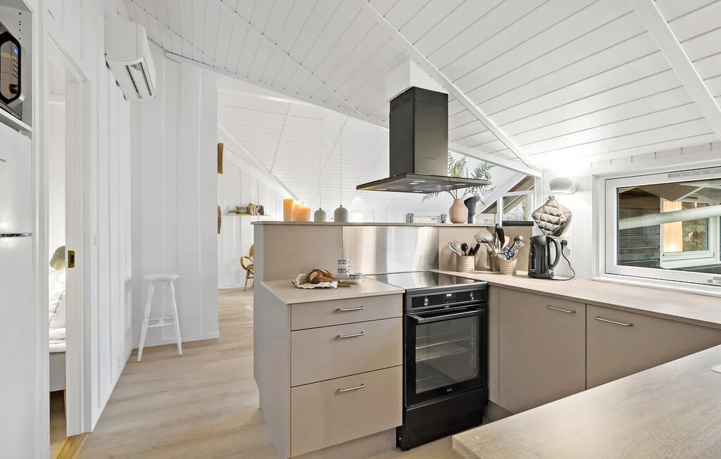 A bright kitchen with a central island, oven, and sloped white ceiling.
