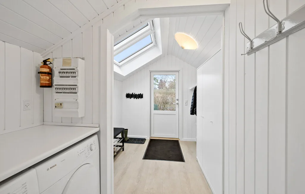A bright laundry room with a washer and dryer beneath a sloped ceiling.