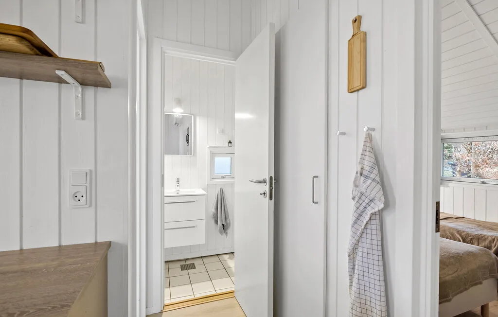 A white-paneled hallway opens onto a bathroom and a bedroom.