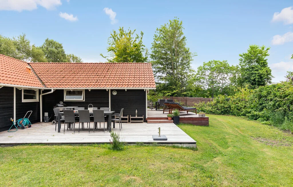 Outdoor patio beside a dark house, with a dining table and grassy yard.