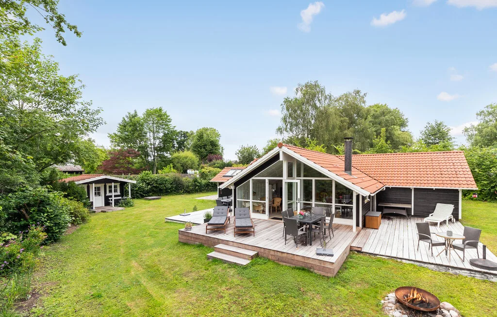 A modern house with a wooden deck sits in a green garden.