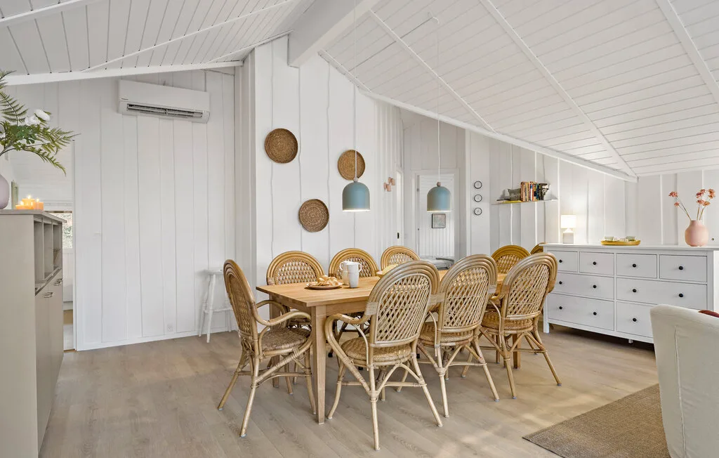 Dining area with a wooden table and woven seating beneath a sloped ceiling.
