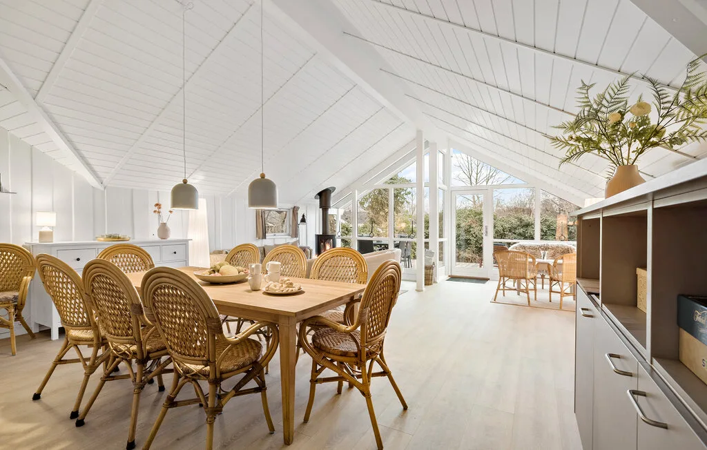 A bright dining area with wicker seating and large windows opening onto a patio.