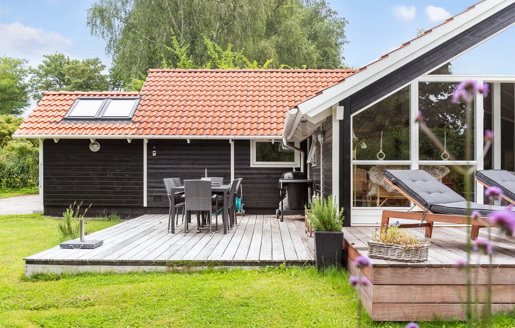 A wooden house opens onto a deck with outdoor dining and lounge seating.