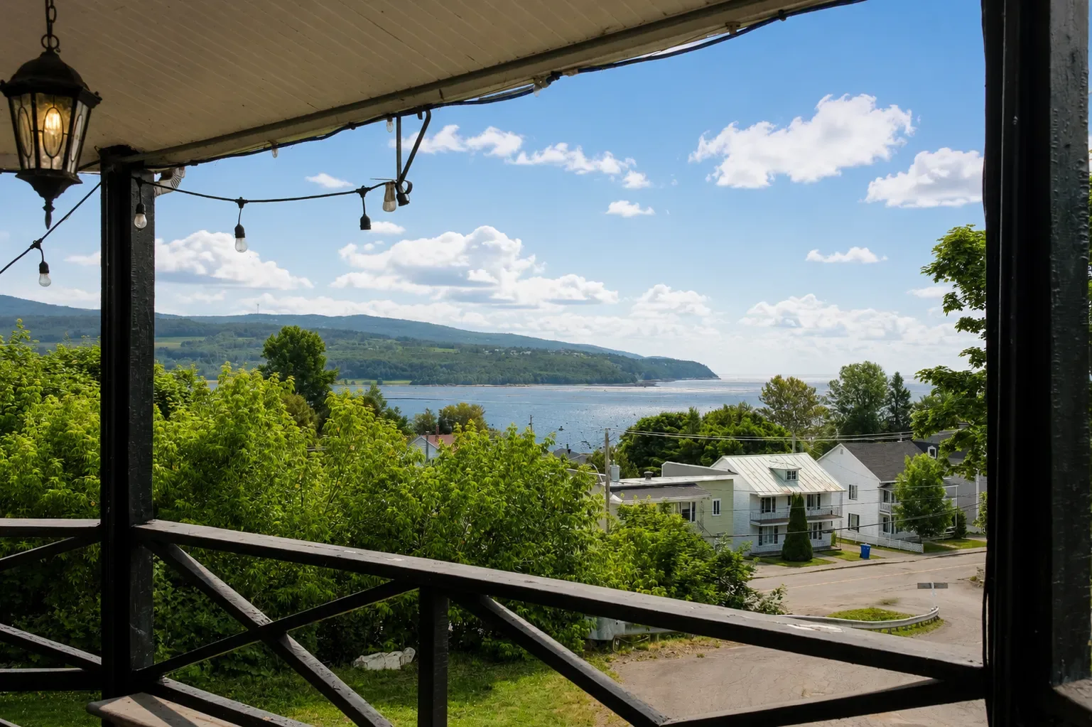 Balcony overlooking a blue bay and green coastline under a clear sky