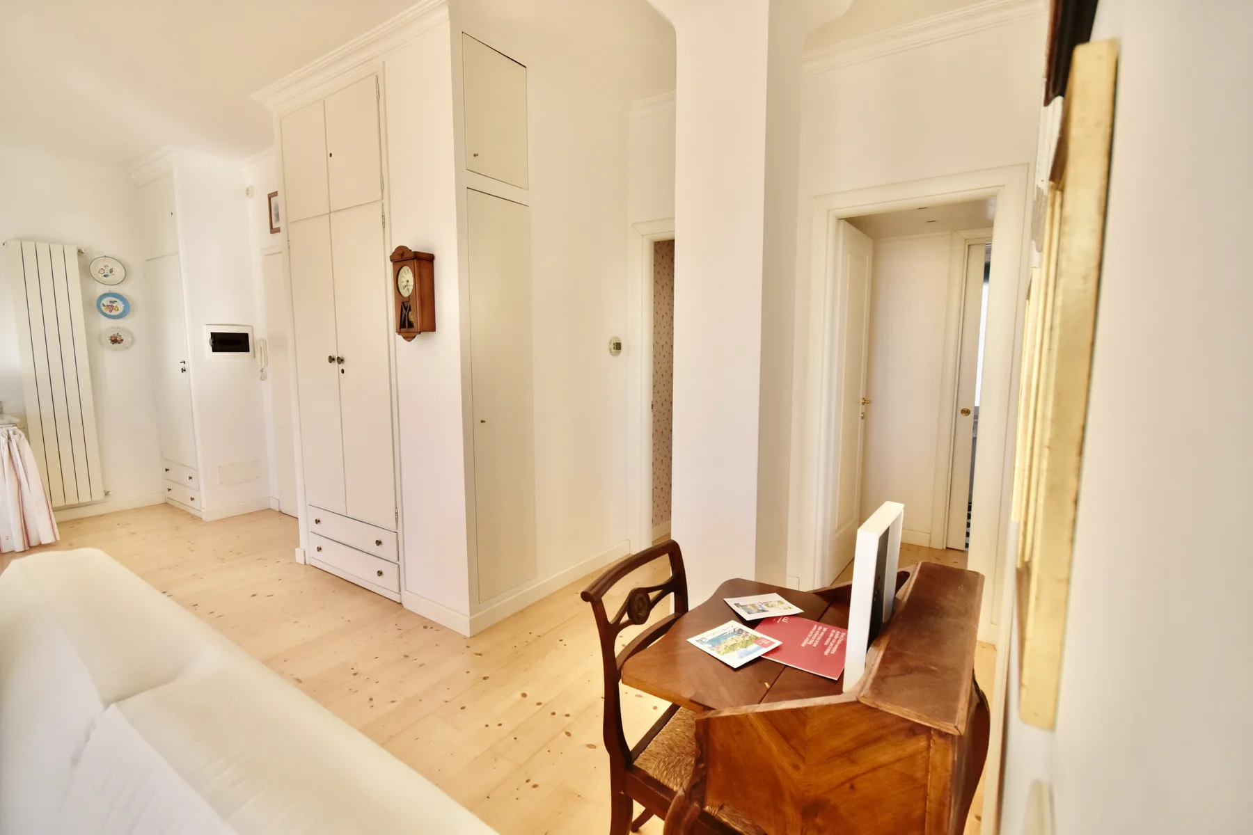 A bright room with a wooden desk, chair, and built-in cupboards.