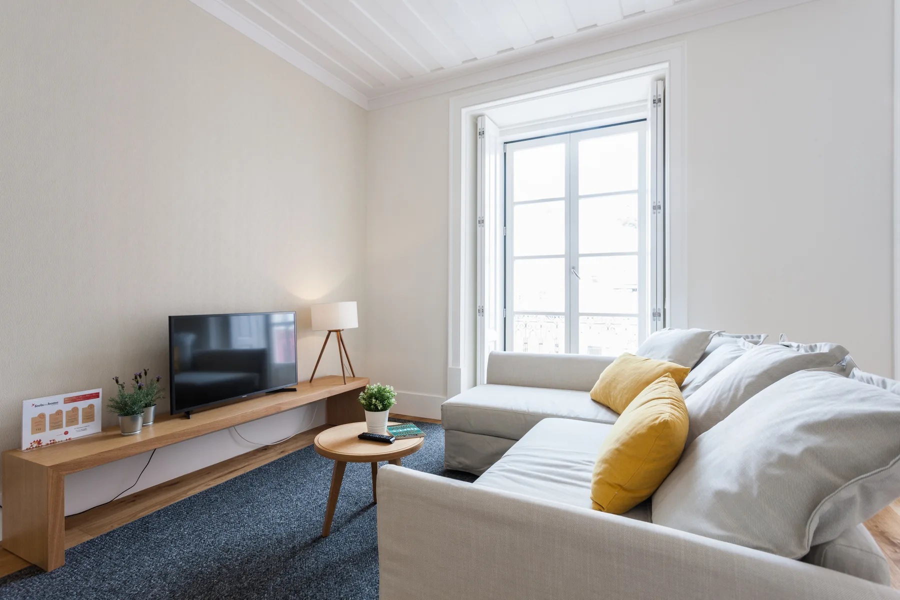 Una sala luminosa con un televisor, asientos y una ventana grande.