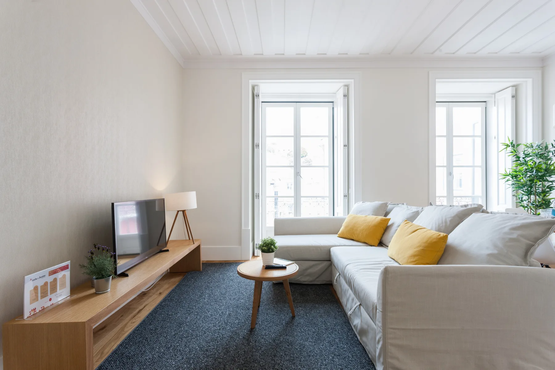 Una sala luminosa con asientos, un televisor y ventanas altas.