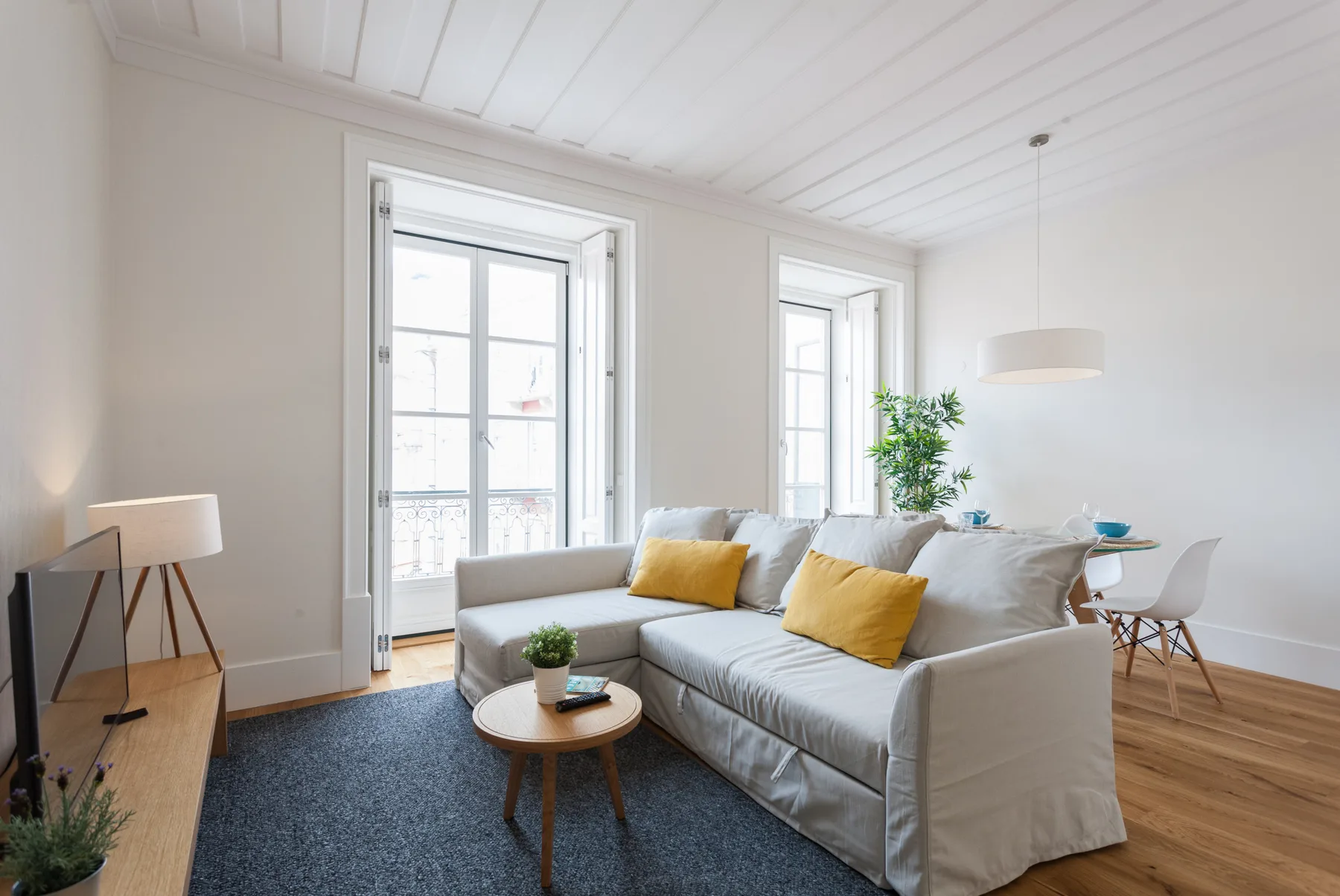 Sala de estar con asientos, una mesa de centro y ventanas altas.