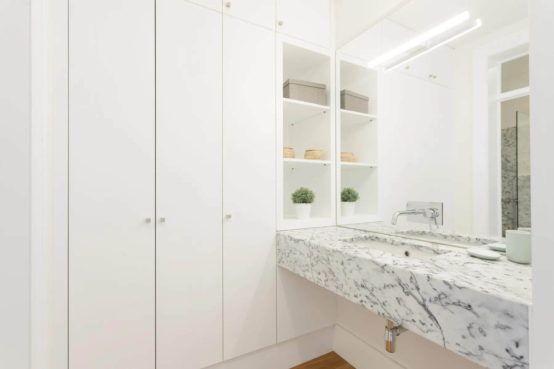 Un baño luminoso con una amplia encimera, lavabo y armarios con espejo.