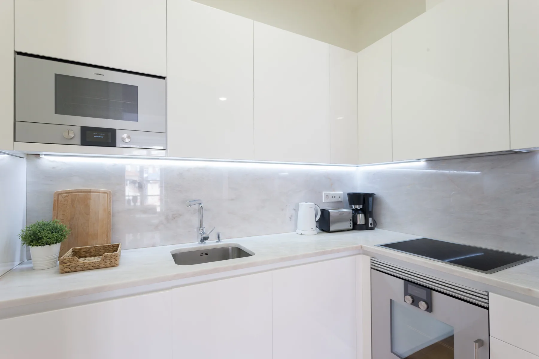 Una cocina moderna con armarios blancos, una encimera y electrodomésticos integrados.