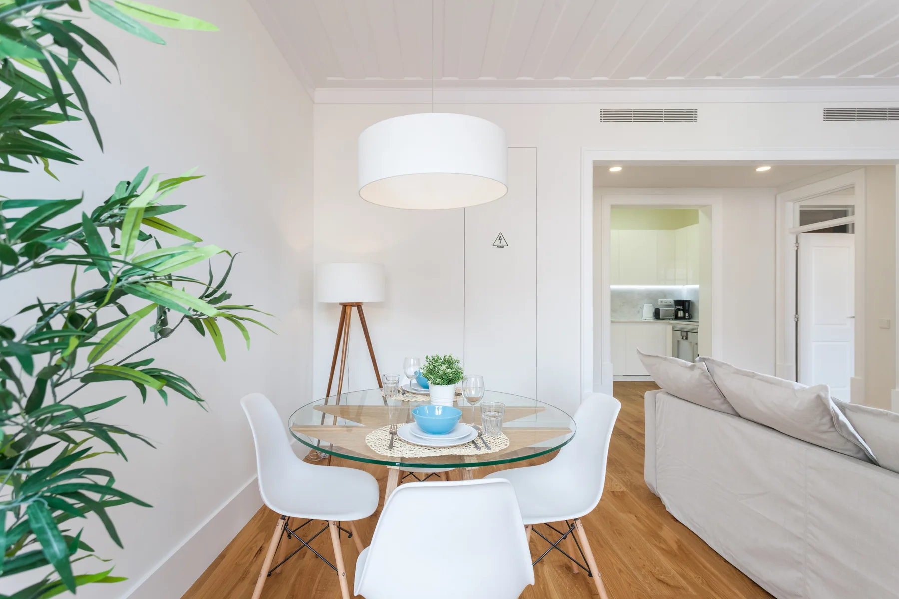 Una luminosa zona de estar y comedor con una mesa de cristal y asientos claros.