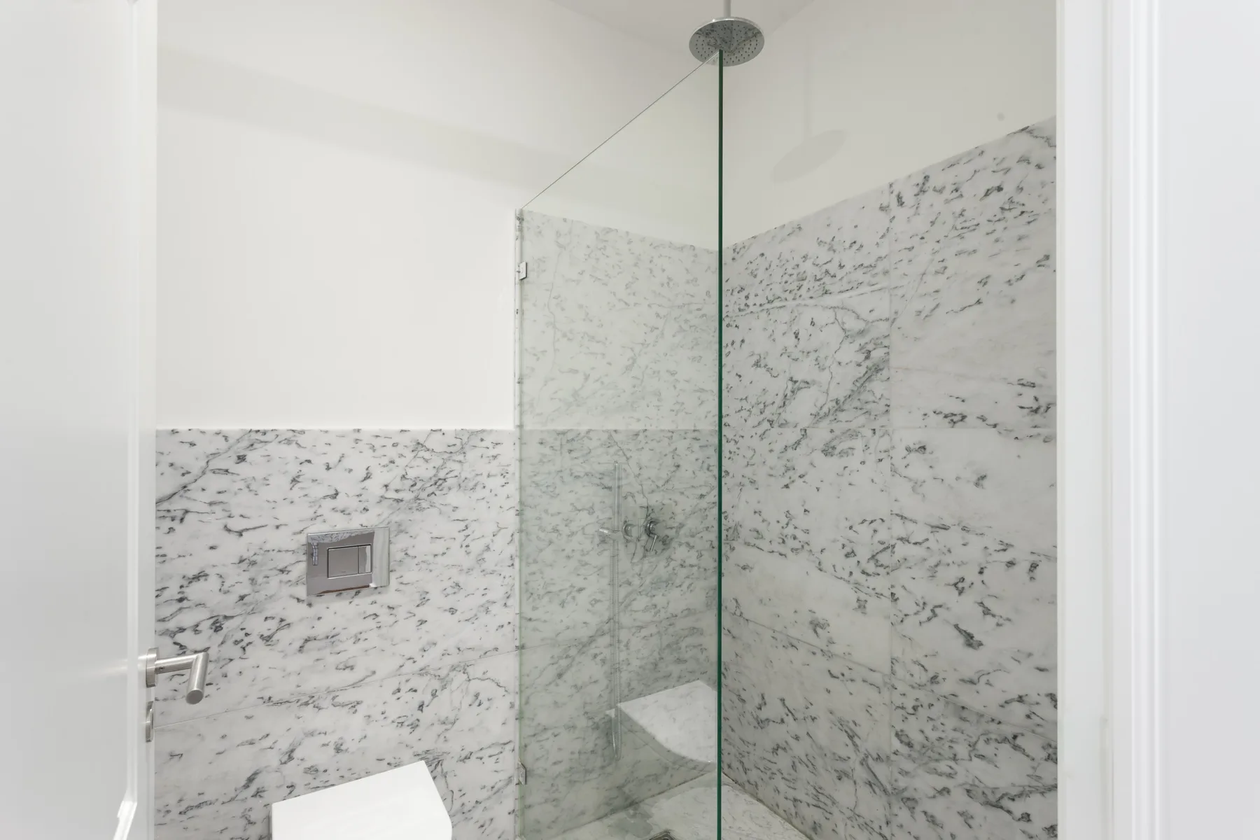 Un baño con una ducha de vidrio y azulejos estampados en las paredes.