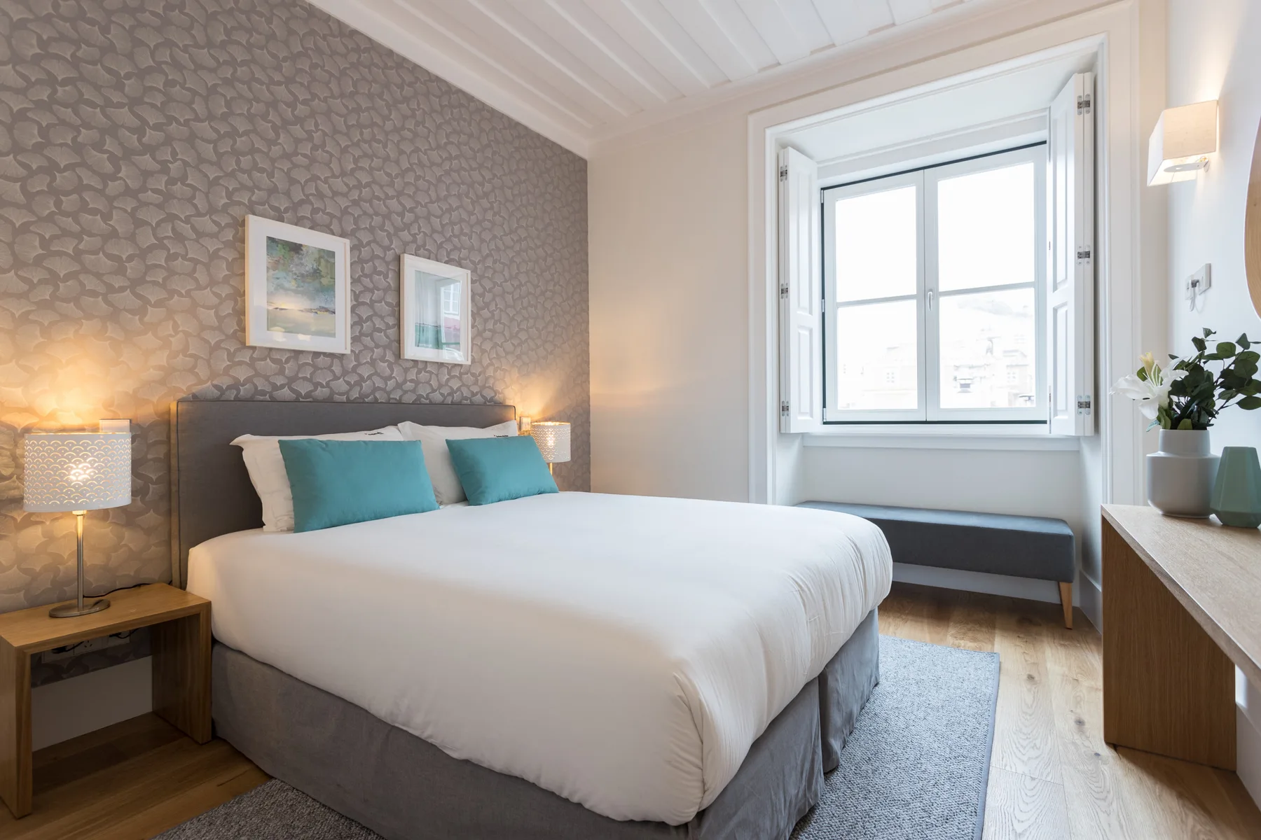 Un dormitorio con una cama bien arreglada y una ventana grande.