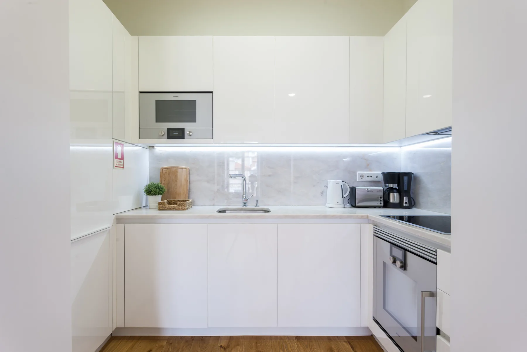 Una cocina moderna y luminosa con armarios blancos y electrodomésticos integrados.