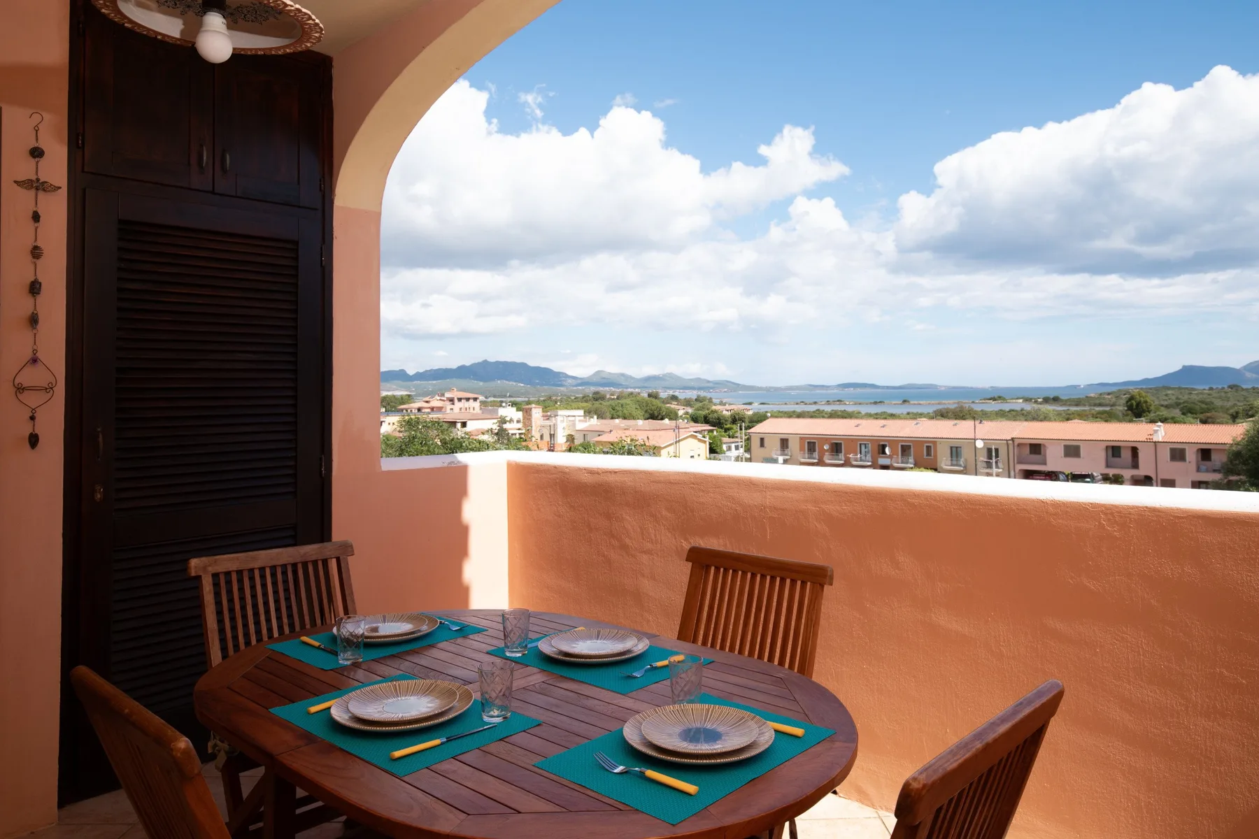 Un comedor en el balcón con una mesa redonda frente a una amplia vista del cielo y colinas lejanas.