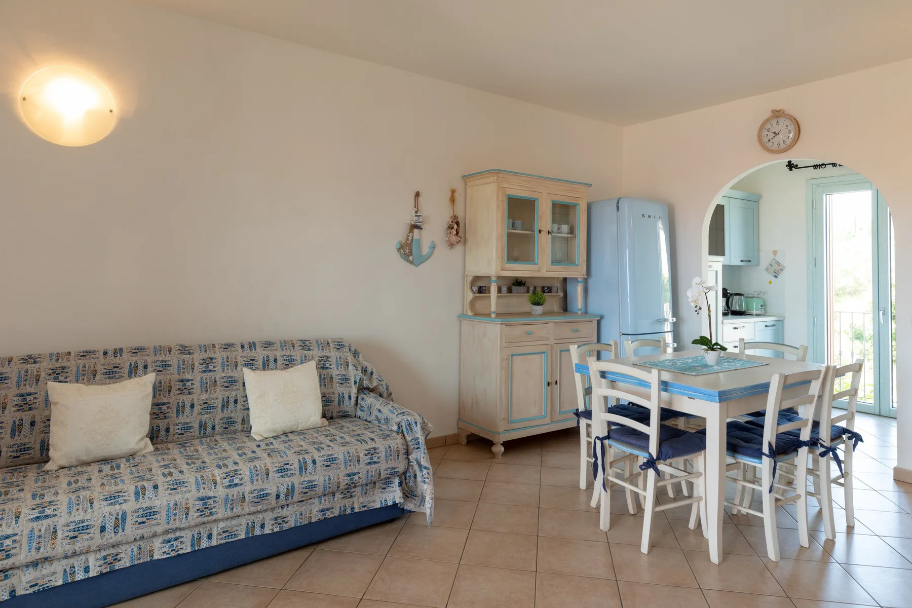 Zona de estar y comedor con asientos estampados y una mesa junto a la cocina.