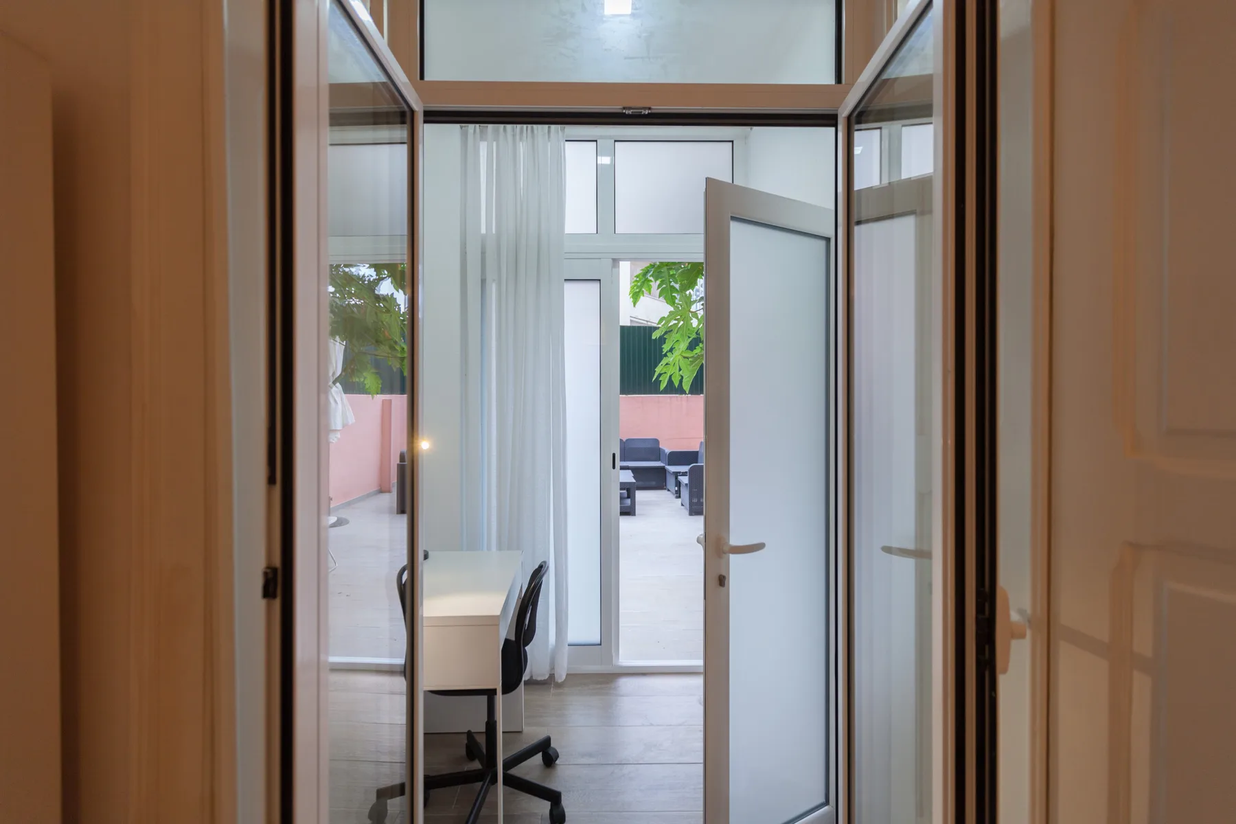 A bright room with glass doors opening onto an outdoor patio.