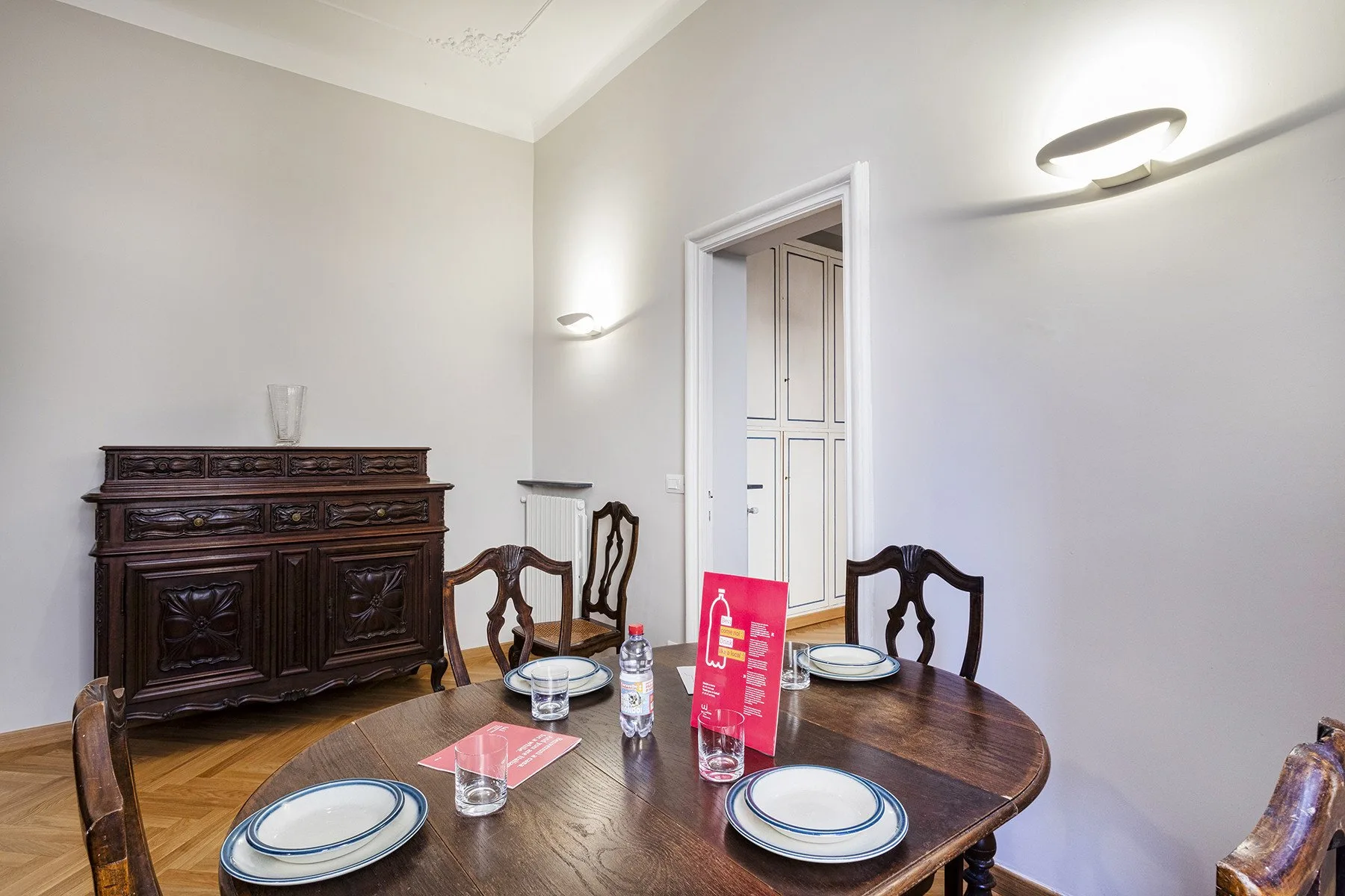 A dining room with a round wooden table and dark carved sideboard.