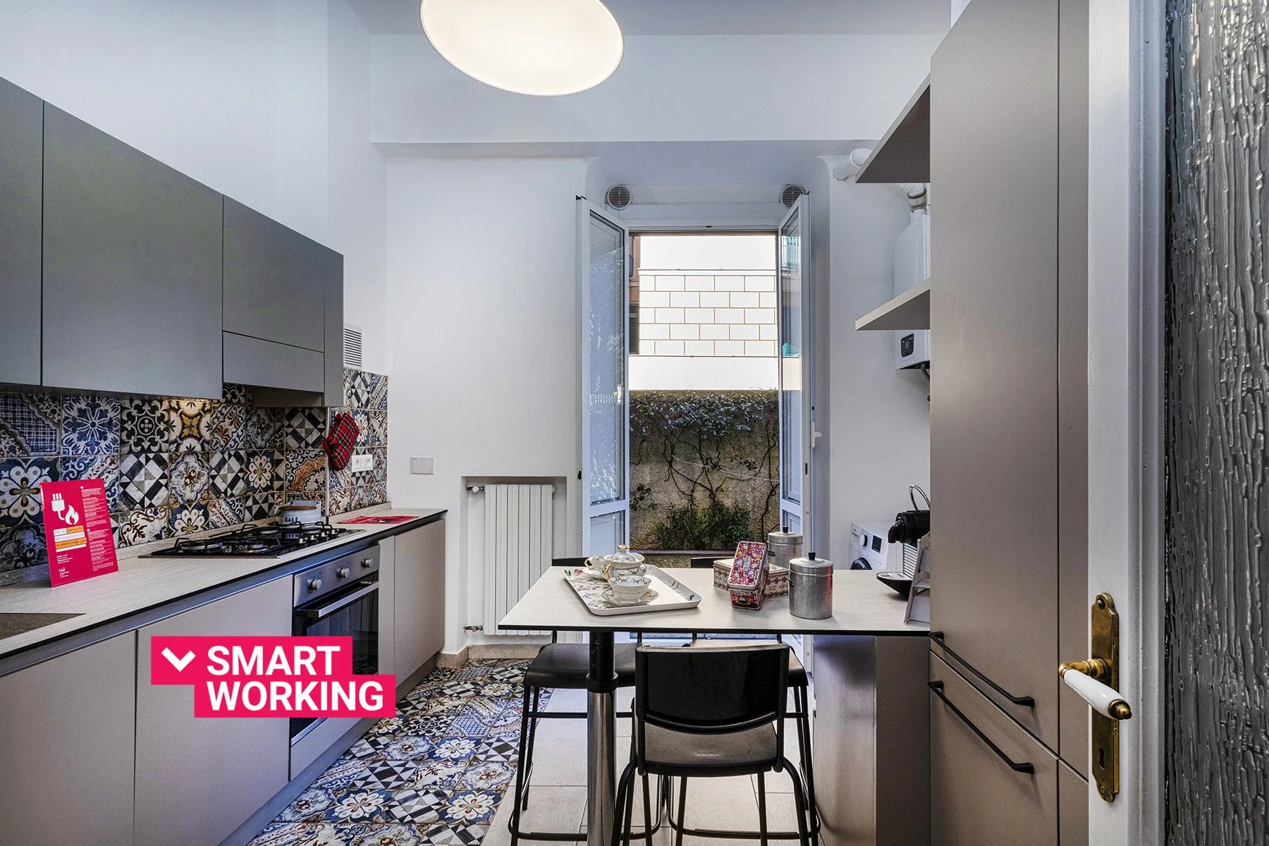 A compact kitchen with patterned tile, cabinets, and a small dining table.