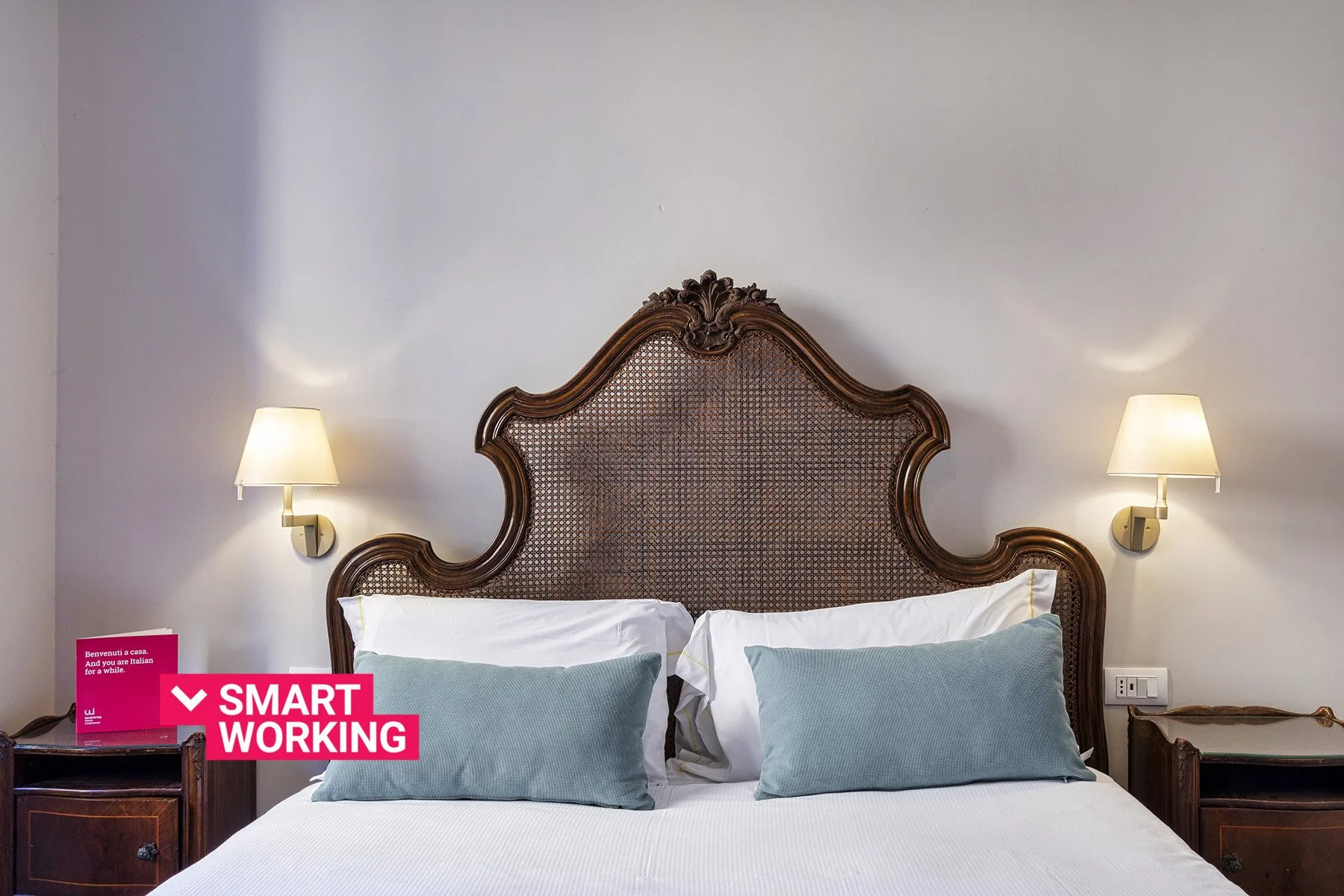A bedroom with a bed, an ornate headboard, and matching wall lamps.