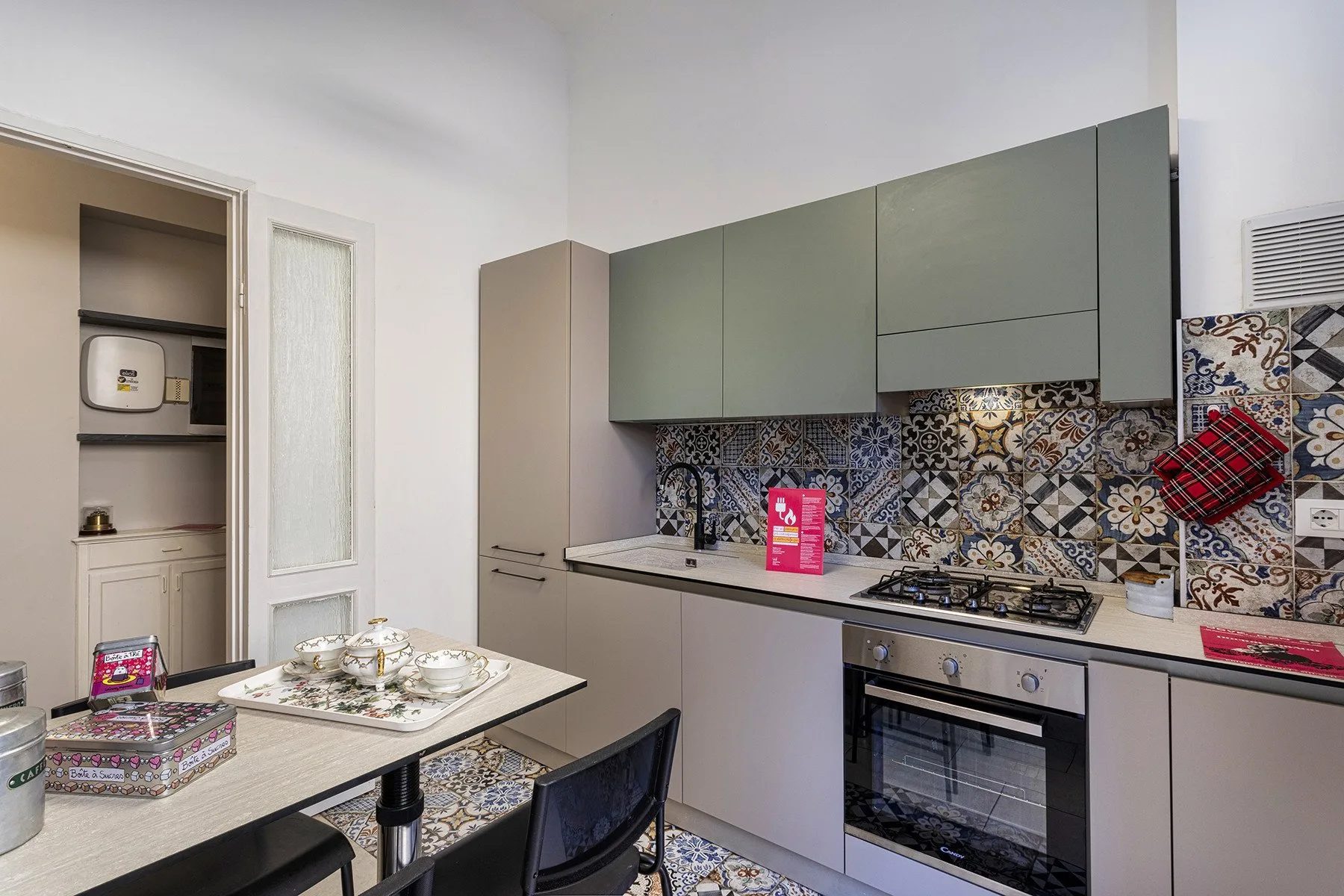A kitchen with gray cabinets, a patterned backsplash, and a dining table.