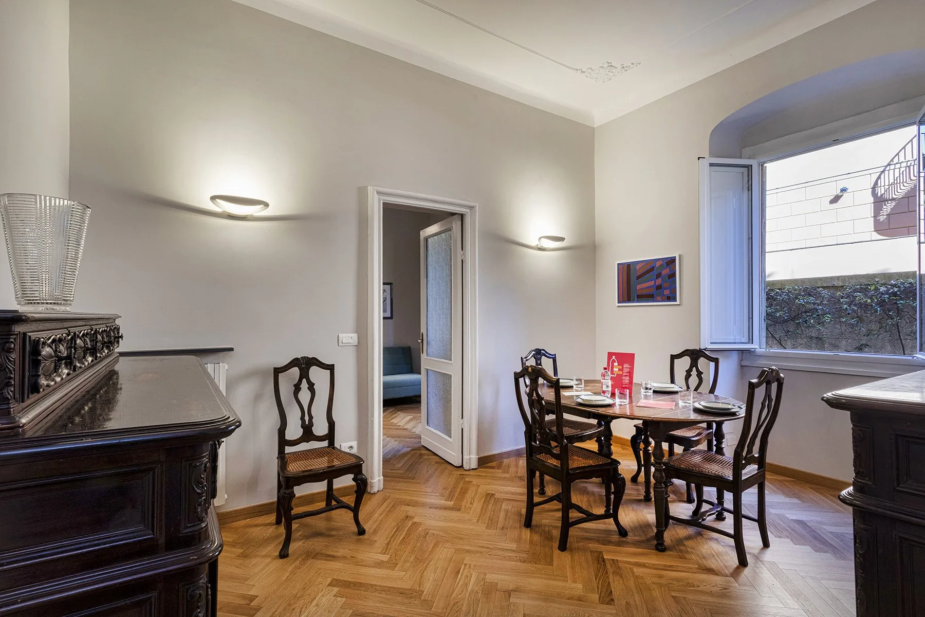 A dining room with a wooden table and chairs beside an open window.