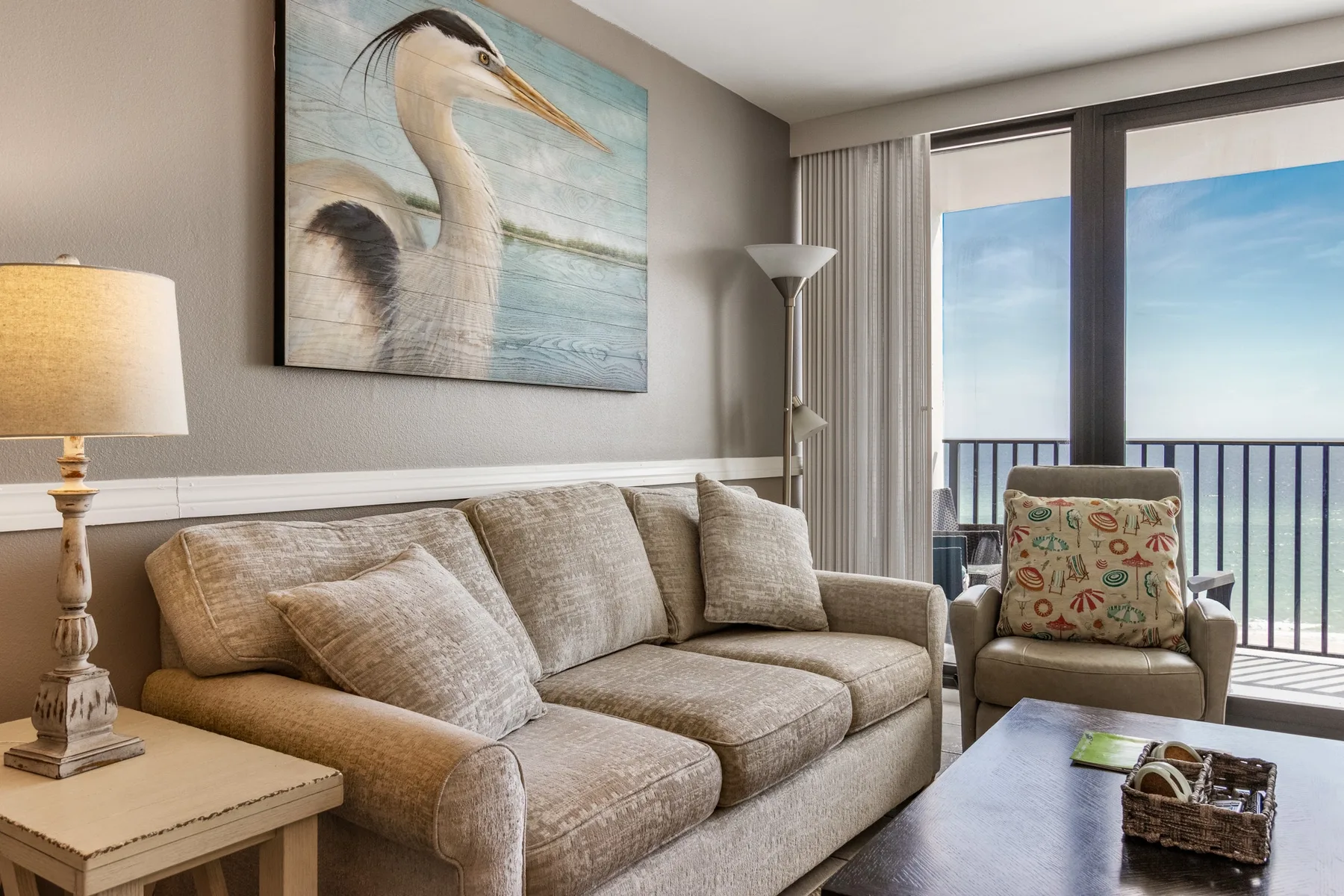 A living room with seating beside large windows overlooking a balcony.