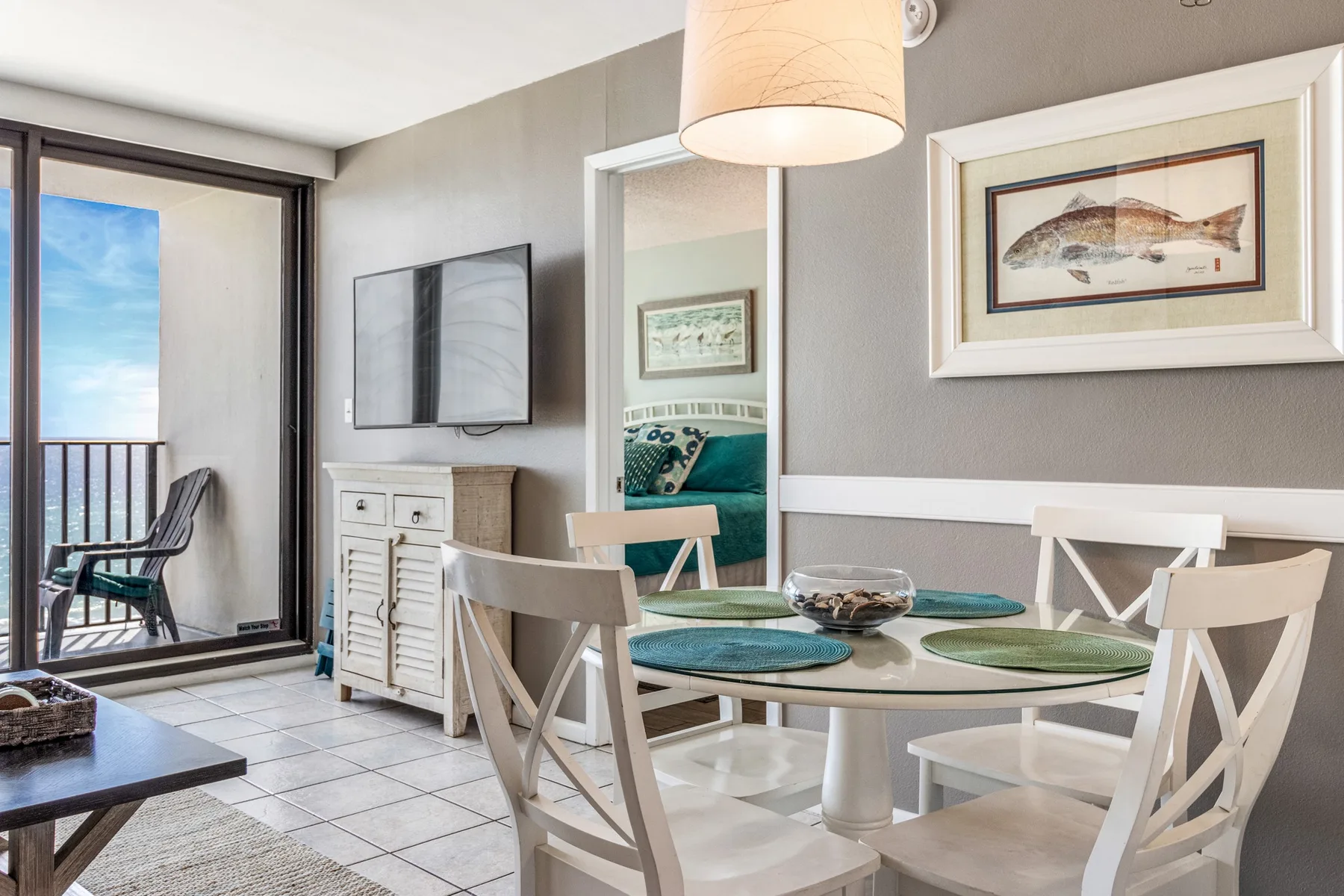 A bright dining area with a round table and glass doors opening to a balcony.