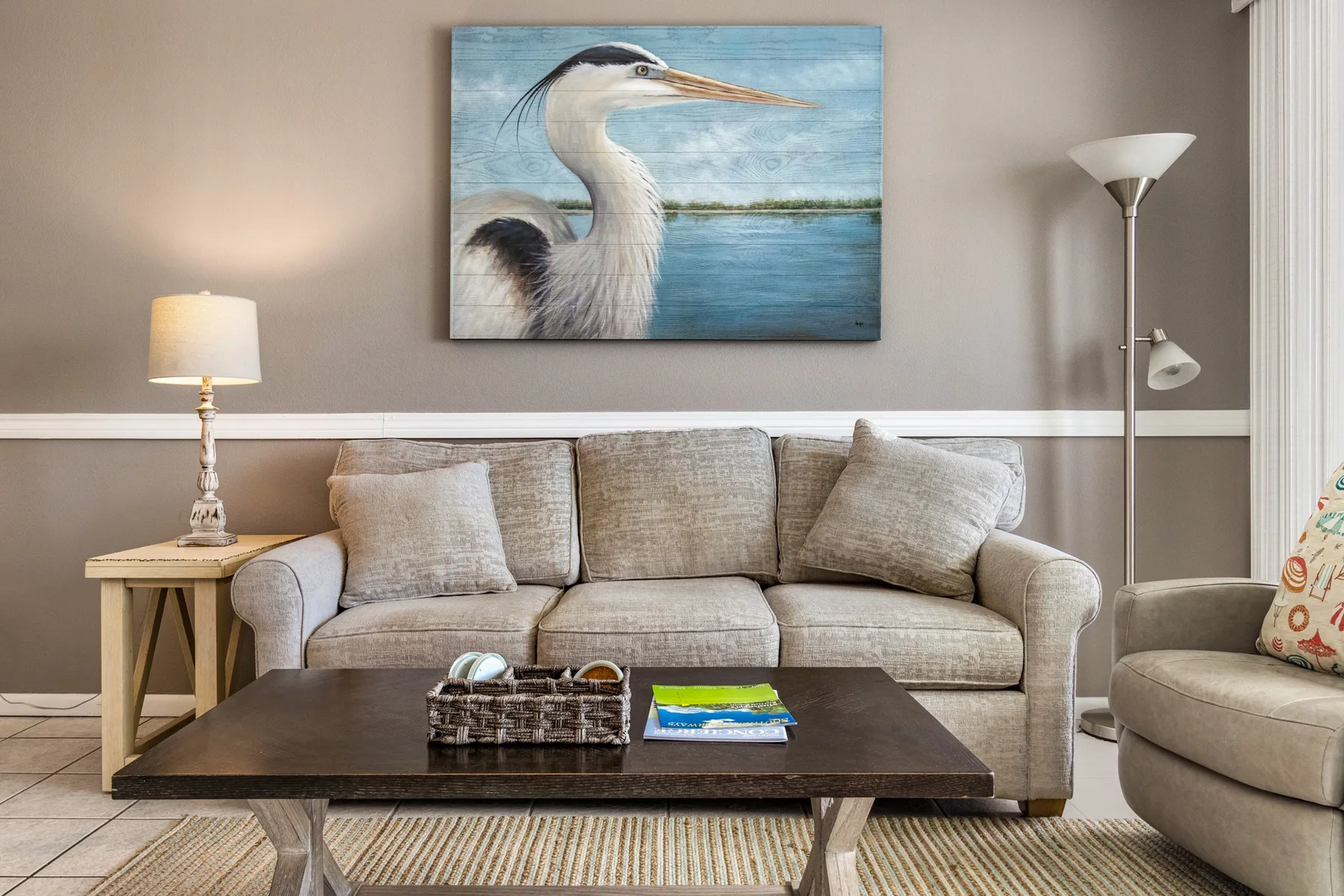 A living room with a sofa, coffee table, and heron artwork on the wall.